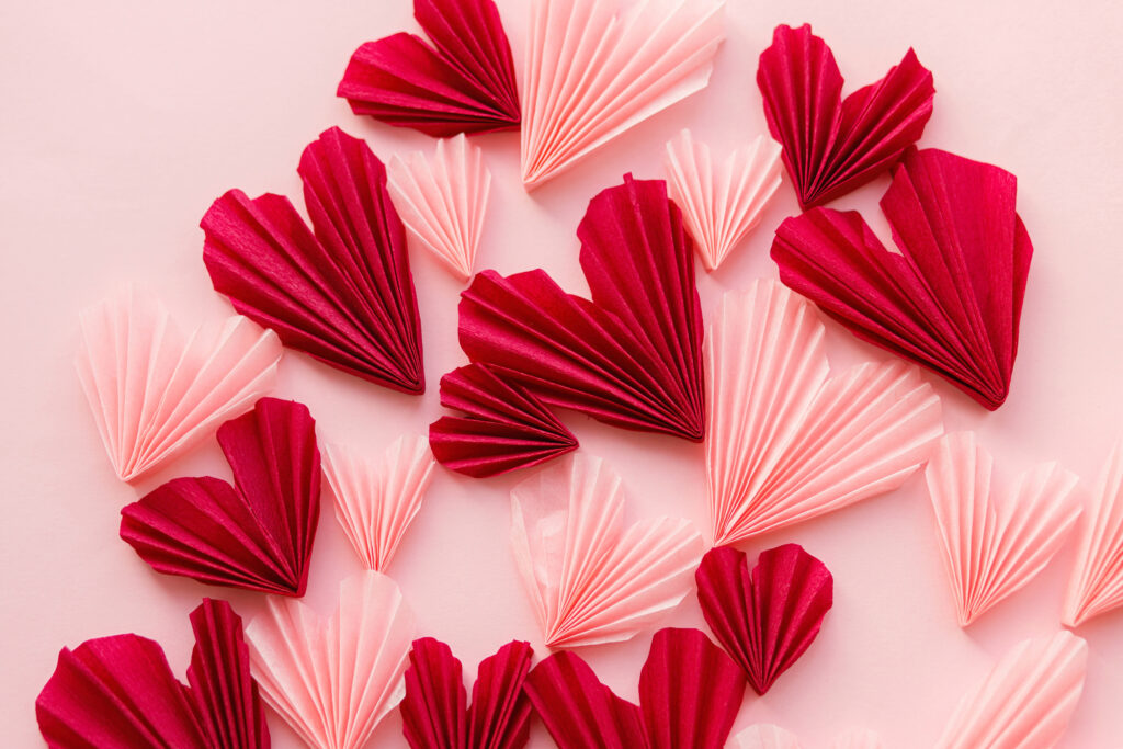 Stylish pink and red hearts flat lay on pink paper background. Creative modern valentines hearts cutouts composition. Love background