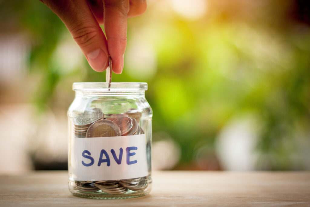 Hand putting coins in a savings jar