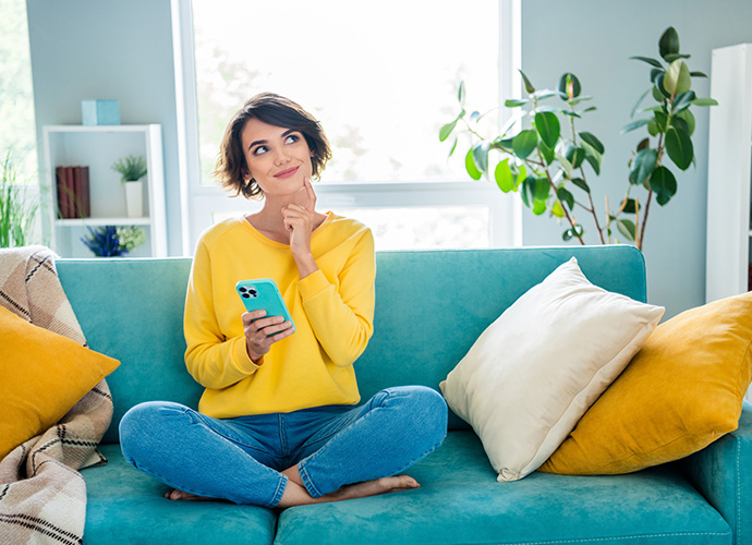 Student sat on a sofa using her phone 