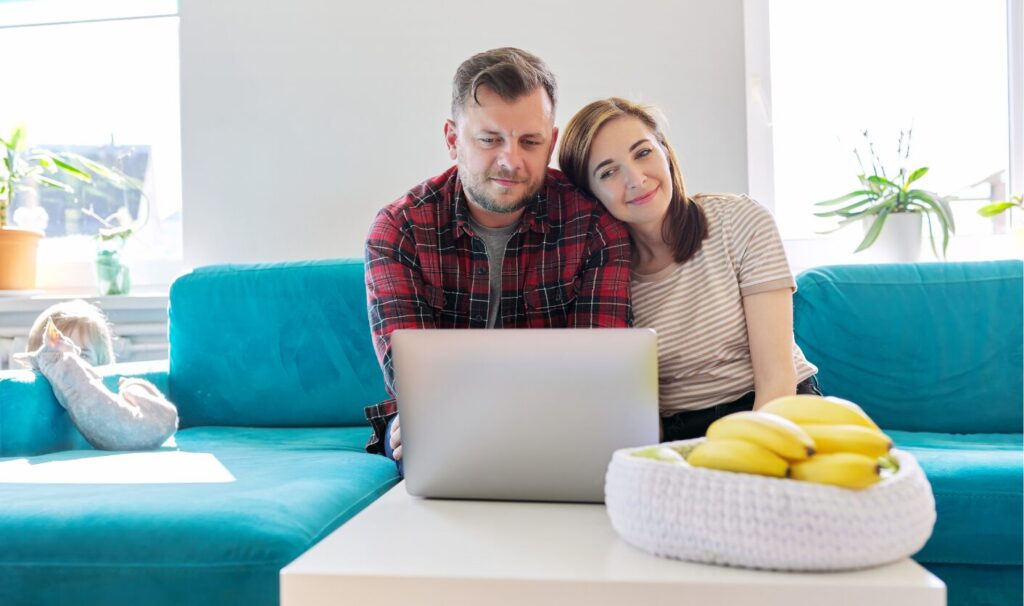 Couple searching for homes for sale online on a laptop.