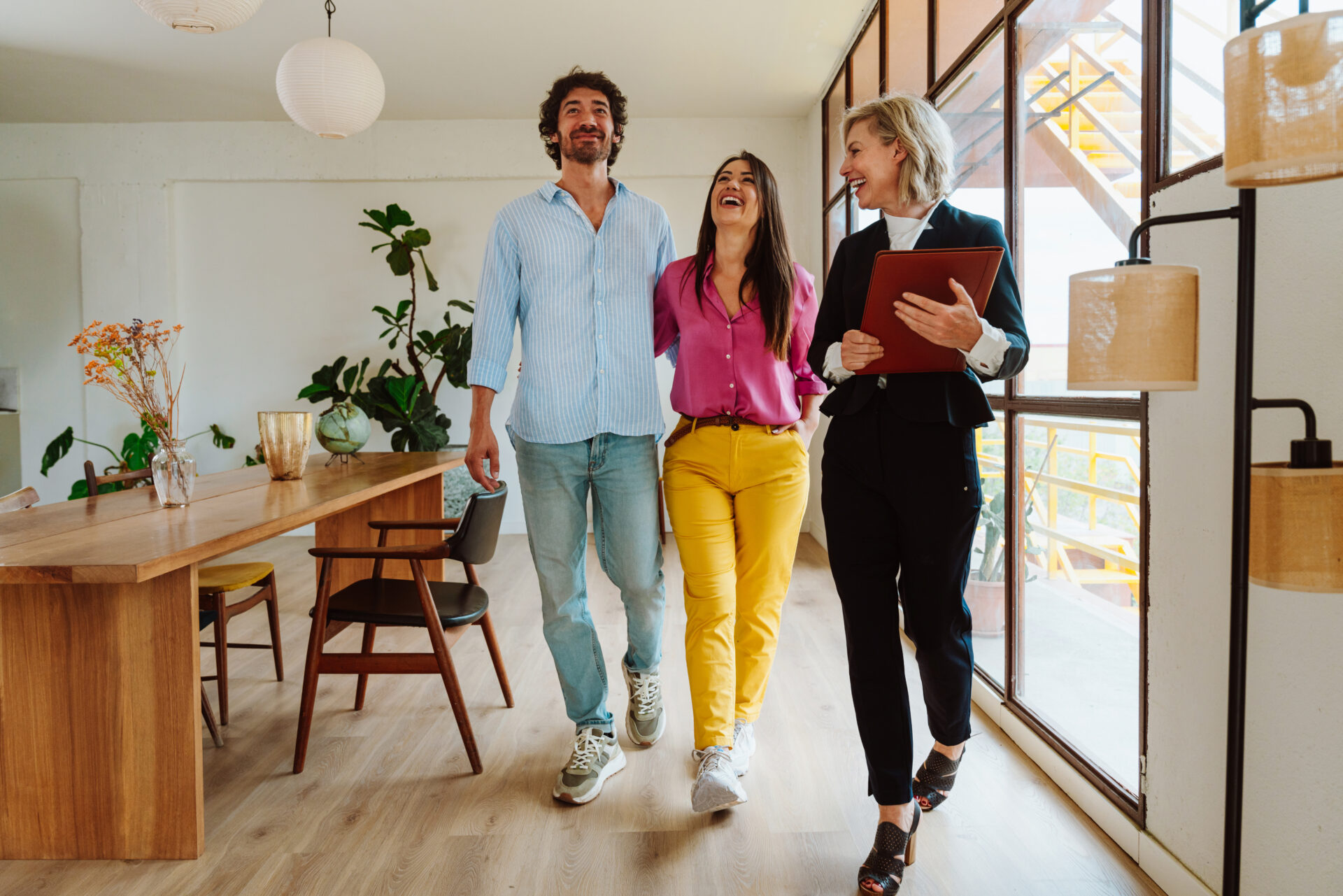 Estate agent showing a smiling couple around a modern home during a viewing