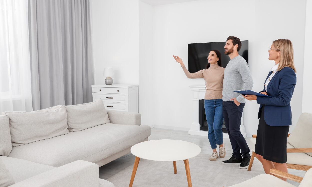 A property agent showing a couple around a bright living room, representing buyers and renters exploring homes and lifestyle options while living in Wimborne BH21.