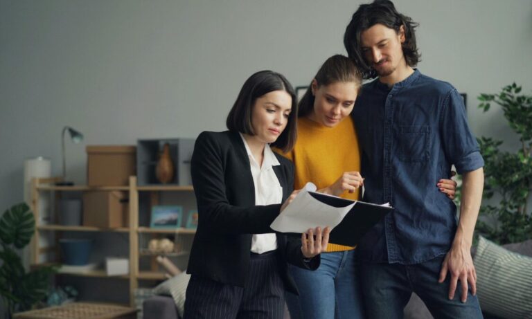 An estate agent discussing property documents with a couple during a home viewing in Merley BH21.