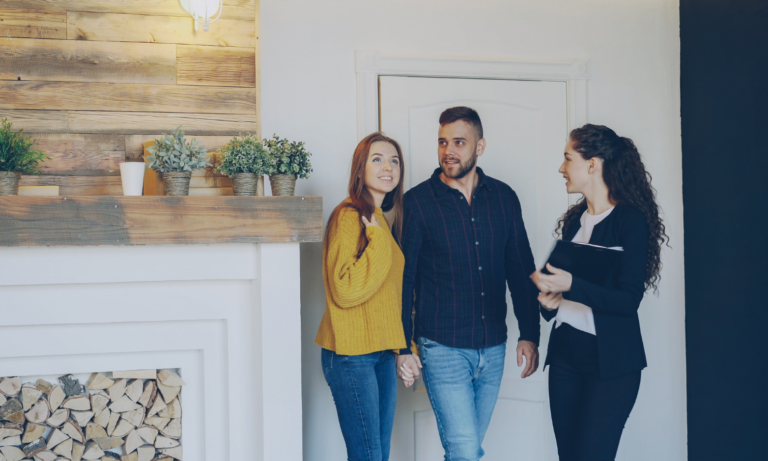 Couple speaking with an estate agent while viewing the interior of a bright, well-presented home.