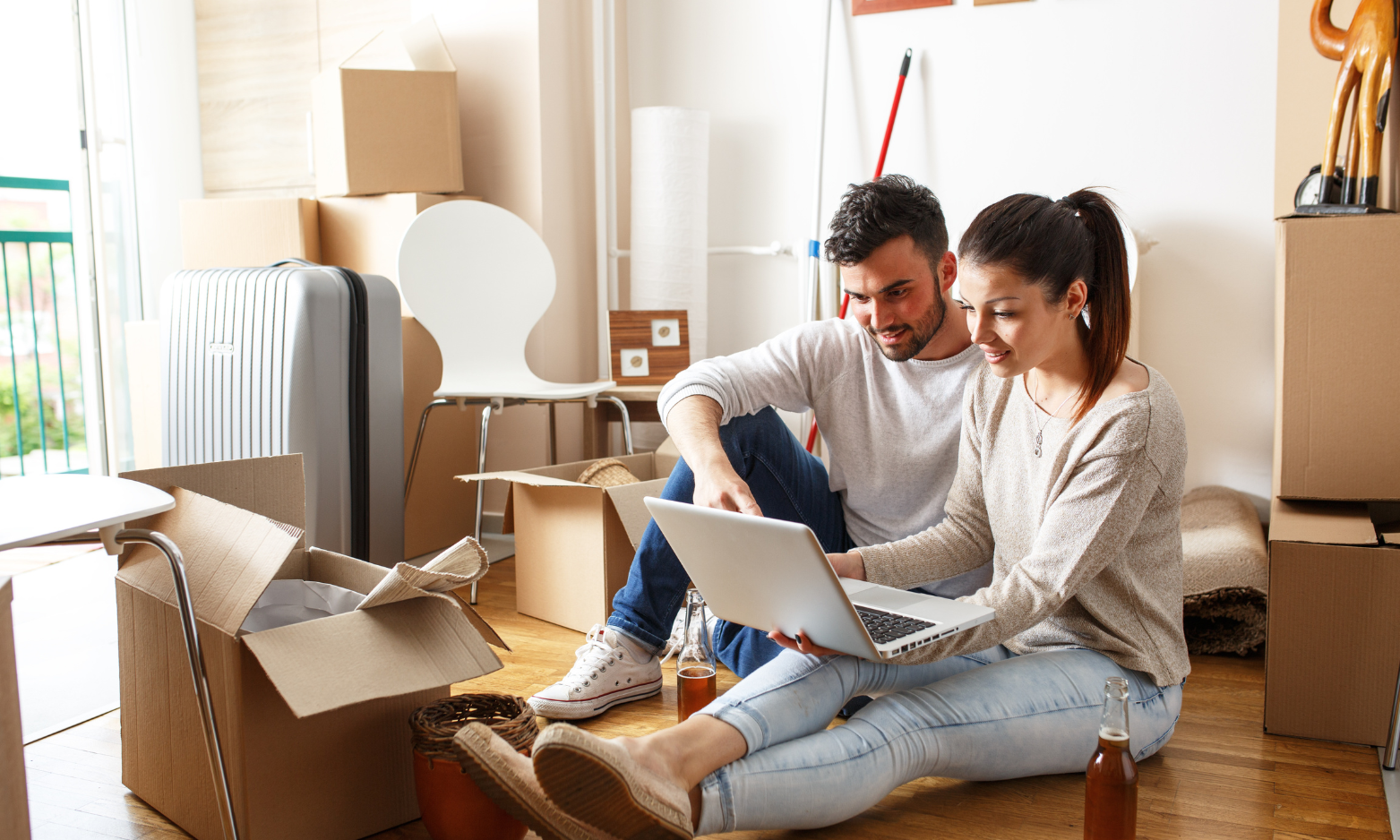 Young couple using a laptop while surrounded by moving boxes in their new home.