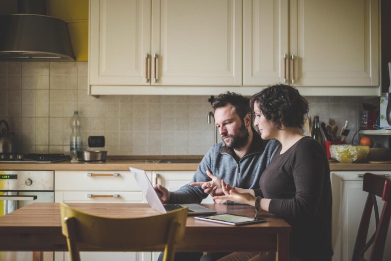Couple at a table using a laptop to research homes and planning changes in Leicester's LE6, LE8 and LE9 postcodes
